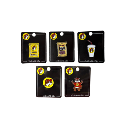 Five Buc-ee's collectible enamel pins on black display cards: Beaver Nuggets bag, beef jerky package, fountain drink cup, classic yellow logo, and full-body Bucky character
